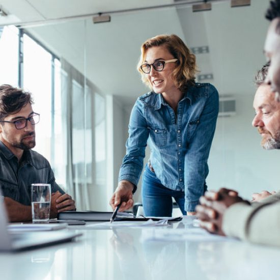 Businesswoman explaining to coworkers about project in office. Beautiful woman explaining her ideas to colleagues in conference room.